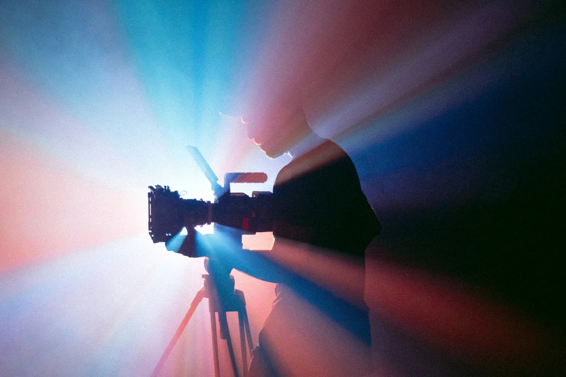 Persona grabando con una cámara sobre trípode bajo luz azul y roja