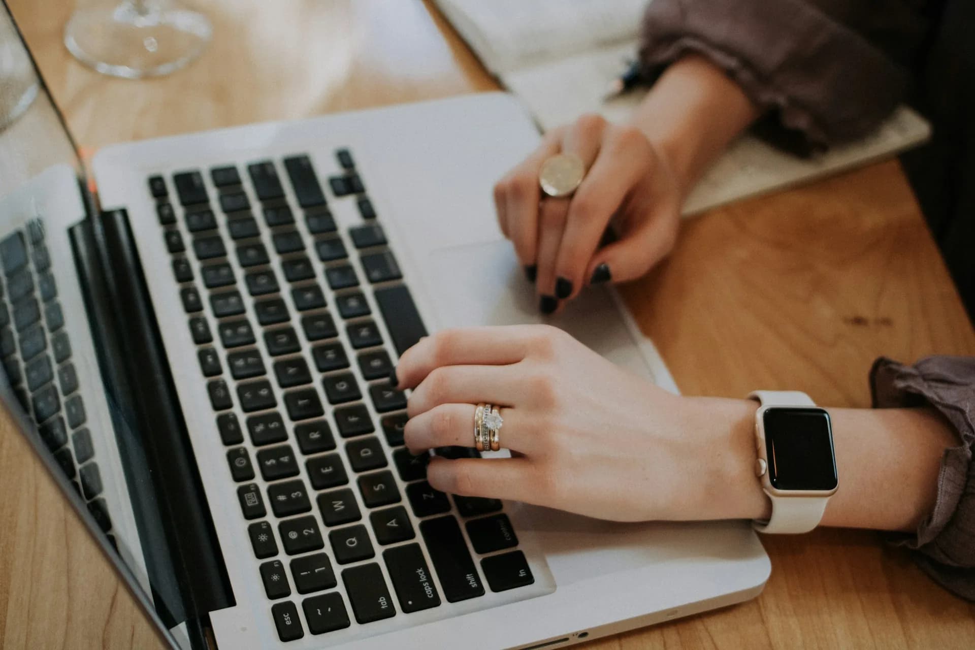 Persona tomando notas con un portátil sobre un escritorio de trabajo